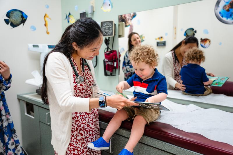 a pediatrician helping a boy read a book