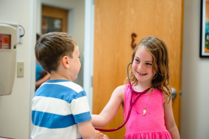 a girl wearing a stethoscope listening to a boys heart